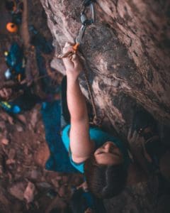 A person clipping a bolt while lead climbing